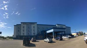 un gran edificio con coches estacionados en un estacionamiento en Stars Inn and Suites - Hotel, en Fort Saskatchewan