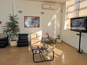 a living room with a flat screen tv and chairs at Hotel Tres Cruces in Montevideo