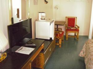 a room with a desk with a television and a room with a table at Capricorn Motel Royale 1000 Islands in Lansdowne
