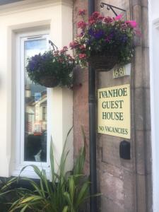 a sign on the side of a house with flowers at Ivanhoe Guest House in Inverness