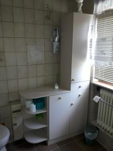 a bathroom with white cabinets and a toilet and a window at Fewo Mueller in Saarlouis
