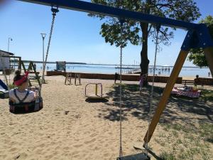 a child sitting in a swing at the beach at Tawerna Panorama in Stepnica