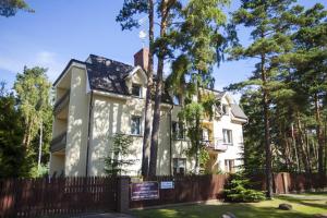 a white house with a fence and trees at Przy Lesie Apartamenty Pokoje Parking in Pobierowo