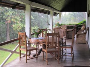 - une table et des chaises en bois sur une terrasse couverte dans l'établissement Ngare Sero Mountain Lodge, à Usa River