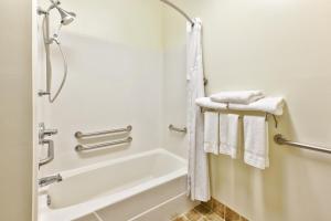 een badkamer met een bad, een douche en handdoeken bij Country Inn & Suites by Radisson Benton Harbor-St Joseph MI in Benton Harbor