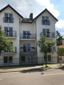 a white building with black balconies on a street at Willa Wena in Ustka