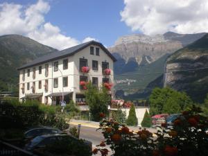 a white building with flowers on the windows and mountains at Hotel Bellavista Ordesa in Torla-Ordesa
