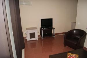 ein Wohnzimmer mit einem TV und einem Stuhl in der Unterkunft Hotel Doña Luisa in San Luis de Sabinillas