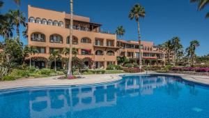 a resort with a large swimming pool in front of a building at Condominios Brisa - Ocean Front in Cabo San Lucas