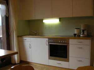 eine Küche mit weißen Schränken, einer Spüle und einem Backofen in der Unterkunft Appartements am Stein in Bezau + 39 Fotos