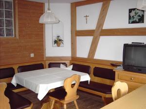 Ein Zimmer mit einem Bett, einem Fernseher und einem Kreuz an der Wand in der Unterkunft Appartements am Stein in Bezau