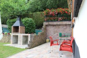 un patio con una mesa, sillas rojas y una pared de piedra. en Apartamento Rural Oizalde, en Elizondo