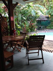 un patio con mesa, sillas y piscina en La Residence, en Mamoudzou