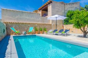 una piscina con sedie e ombrellone accanto a una casa di Ca Na Siona a Vilafranca de Bonany