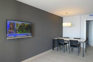 a dining room with a table and a tv on a wall at Rentalmar Miami Palace Plus in Miami Platja