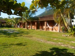 una casa con palmeras frente a un patio en Chalés Ki Bakana, en Ubatuba