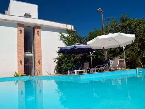 einen Pool mit Stühlen und Sonnenschirmen neben einem Haus in der Unterkunft Pousada Omnimare in Ubatuba
