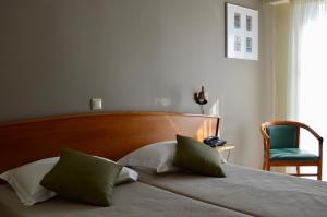 a bed with a wooden headboard and a green chair at Evripides Hotel in Athens