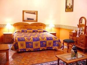 a bedroom with a king sized bed and a table at Hotel Reyna Soledad in Zacatecas