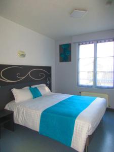 a bedroom with a large bed with blue and white sheets at Le Clos Albert in Loudun