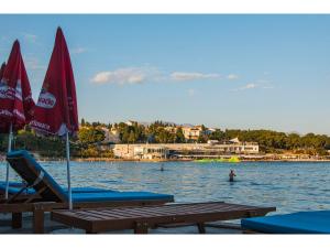 two lounge chairs and umbrellas on a beach with water at IDRO Studio Apartments directly at the beach in Split