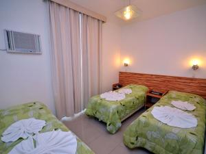 ein Hotelzimmer mit zwei Betten und einem Fenster in der Unterkunft Pousada Omnimare in Ubatuba