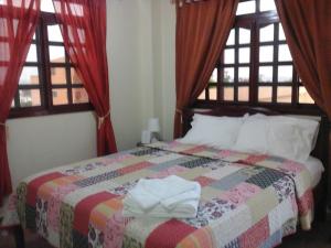 sypialnia z łóżkiem z czerwonymi zasłonami i oknami w obiekcie Puerta Sol Inn w mieście Manglaralto