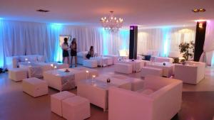 Pokój z białymi krzesłami i stołami oraz żyrandolem w obiekcie Hotel Dos Venados w mieście San Luis