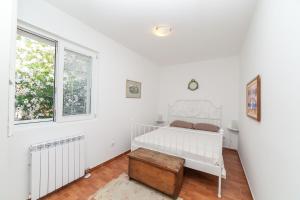 a white bedroom with a bed and a window at Beachfront First Line View in Sveti Stefan