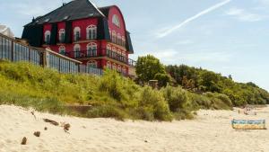 a red and black building on a sandy beach at Bałtyk in Niechorze