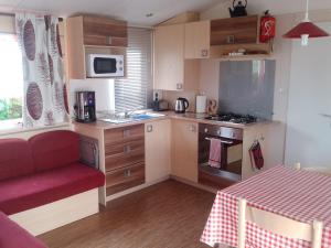 a small kitchen with a table and a red chair at Les Charmettes Mobilhomes17 in Les Mathes
