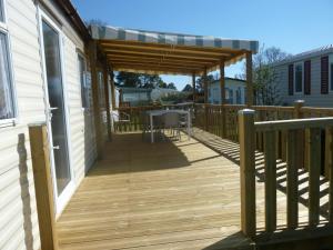 a deck with a pergola on the side of a house at Les Charmettes Mobilhomes17 in Les Mathes