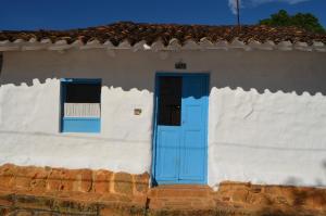 Casa blanca con puerta y ventana azules en Albahaca Hospedaje Tienda, en Barichara