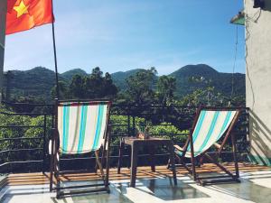 two chairs and a table on a balcony with mountains at Trang Vu Homestay Cu Lao Cham in Tân Hiệp