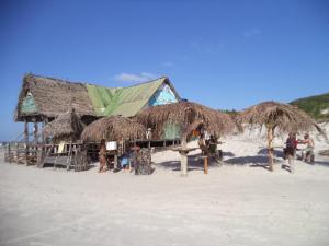 una capanna sulla spiaggia con persone sulla sabbia di Chateu Soneca ad Algodoal