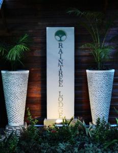 a sign for a hotel with two large vases at Raintree Lodge in Port Moresby