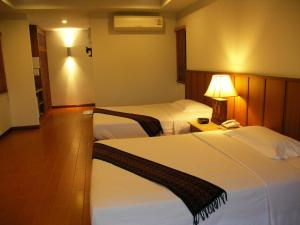 a hotel room with two beds and a lamp at Sailom Resort Bangsaphan in Bang Saphan