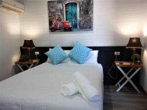 a bedroom with a white bed with blue pillows at Kurri Motor Inn in Kurri Kurri