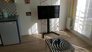 a living room with a television on a stand with a chair at Studio Port Cergy in Cergy
