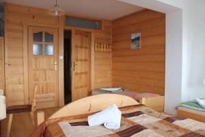 a room with two beds in a room with wooden walls at Pokoje gościnne Kamińscy in Gliczarów
