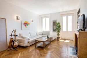 a living room with a white couch and a guitar at Saxe And The City , Downtown Lyon in Lyon
