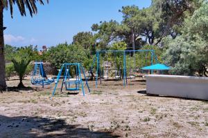 an empty playground with two blue swings at Pefka Rooms in Mytilini