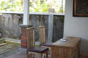 two chairs and a wooden table in a room with a window at Demank Hidden Guesthouse in Ubud