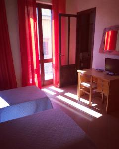 a bedroom with two beds and a desk with a television at La casa di nonna Rosa in Isola delle Femmine