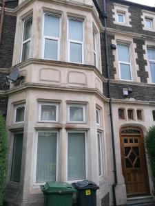 un bâtiment avec une porte et deux poubelles devant lui dans l'établissement Beautiful Victorian house, à Cardiff
