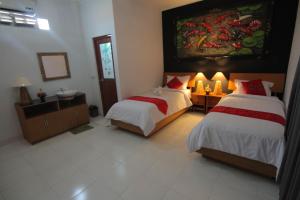 1 dormitorio con 2 camas y un cuadro en la pared en Bubu Inn, en Ubud