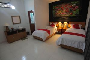 a bedroom with two beds and a painting on the wall at Bubu Inn in Ubud