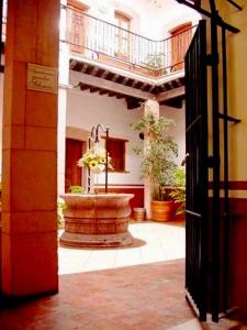 une porte ouverte donnant sur une cour avec une fontaine dans l'établissement Hotel Reyna Soledad, à Zacatecas