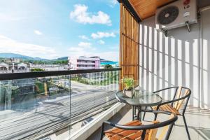 ein Balkon mit einem Glastisch und Stühlen und einer Aussicht in der Unterkunft Lemonade Phuket Hotel -SHA Plus in Chalong 