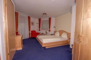 ein Schlafzimmer mit einem Bett und einem roten Stuhl in der Unterkunft Berg & SPA Hotel Urslauerhof in Maria Alm am Steinernen Meer